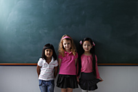 three young girls standing in front of chalk board - Asia Images Group