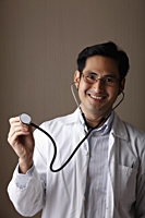 male doctor wearing a stethoscope and smiling - Asia Images Group