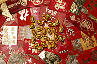 Gold money, ingot scattered on red packets or Hong Baos - Asia Images Group