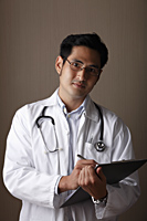 Male doctor holding clip board - Asia Images Group