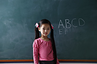 young girl standing in front of chalk board - Asia Images Group