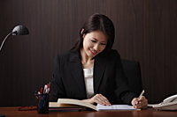 Young woman writing at her desk - Asia Images Group