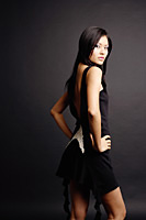 Young woman, hands on hip, looking over shoulder at camera - Asia Images Group