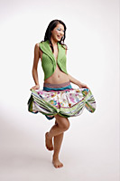 Young woman, standing, smiling, raising skirt - Asia Images Group