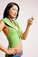 Young woman with mobile phone, hand on hip, looking at camera - Asia Images Group