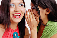 Two women, one looking up, woman next to her whispering - Asia Images Group