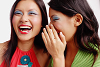 Two women, one laughing, the other whispering in her ear - Asia Images Group
