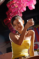 Young woman raising drink, smiling at camera - Asia Images Group
