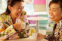 Friends having tea at cafe, laughing - Asia Images Group
