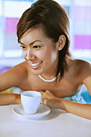Young woman looking away, cup and saucer in front of her - Asia Images Group