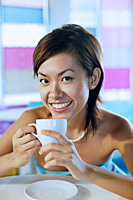 Young woman looking at camera, holding cup and smiling - Asia Images Group