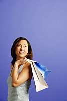 Woman carrying shopping bags over shoulder, looking away - Asia Images Group