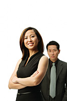 Woman with arms crossed, smiling at camera, man standing behind her - Asia Images Group