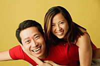 Couple smiling at camera, woman hugging man from behind - Asia Images Group