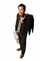 Man standing carrying jacket and briefcase, smiling at camera - Asia Images Group