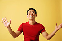 Man smiling, looking up, arms outstretched - Asia Images Group