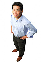 Man standing with hands on hips, smiling at camera - Asia Images Group