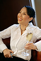 Woman with champagne glass and mobile phone, looking away, smiling - Asia Images Group