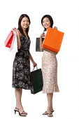 Two young women carrying shopping bags, looking at camera - Asia Images Group