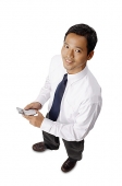 Young executive, holding mobile phone, looking at camera - Asia Images Group