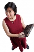 Woman looking at camera, holding abacus - Asia Images Group