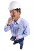 Mature man wearing construction hat, holding PDA, hand on chin - Asia Images Group