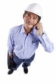 Mature man wearing construction hat, using mobile phone - Asia Images Group