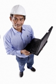 Mature man wearing construction hat, holding laptop, looking at camera - Asia Images Group