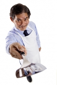 Mature man wearing apron, pointing spatula at camera - Asia Images Group