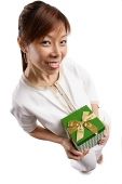 Woman standing, holding gift, looking at camera - Asia Images Group