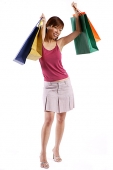 Woman standing, raising shopping bags - Asia Images Group