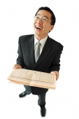 Businessman holding newspaper, laughing - Asia Images Group