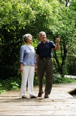 Senior couple standing in park, man pointing - Asia Images Group