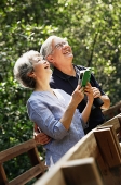 Senior couple side by side, looking up, woman holding book - Asia Images Group