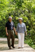 Mature couple walking through park, holding hands - Asia Images Group