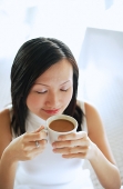 Young woman, holding cup of coffee, eyes closed - Asia Images Group