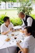 Couple in restaurant, man handing payment to waiter - Asia Images Group