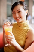 Woman looking at camera, holding drink, smiling - Asia Images Group