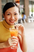 Woman smiling at camera, holding drink, portrait - Asia Images Group