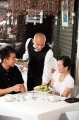 Waiter serving couple at restaurant - Asia Images Group