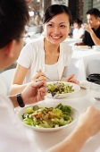 Couple eating at restaurant, over the shoulder view - Asia Images Group
