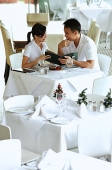 Couple in restaurant, holding menu - Asia Images Group