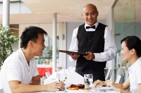 Couple in restaurant, waiter standing next to their table - Asia Images Group