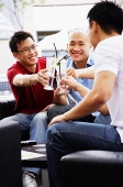 Three guys toasting with drinks - Asia Images Group