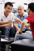 Three guys at a cafe, toasting with drinks - Asia Images Group
