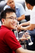 Man holding drink, turning to look at camera - Asia Images Group