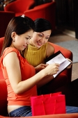 Two women sitting, looking at book - Asia Images Group