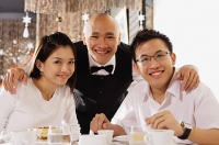 Waiter with couple at restaurant, looking at camera, smiling - Asia Images Group