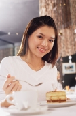 Woman looking at camera, dessert in front of her - Asia Images Group