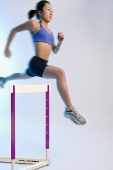 Woman jumping over hurdle - Asia Images Group